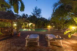 A pool area with lounge chairs and a thatched-roof structure. - Ladda Resort (Takua Pa)