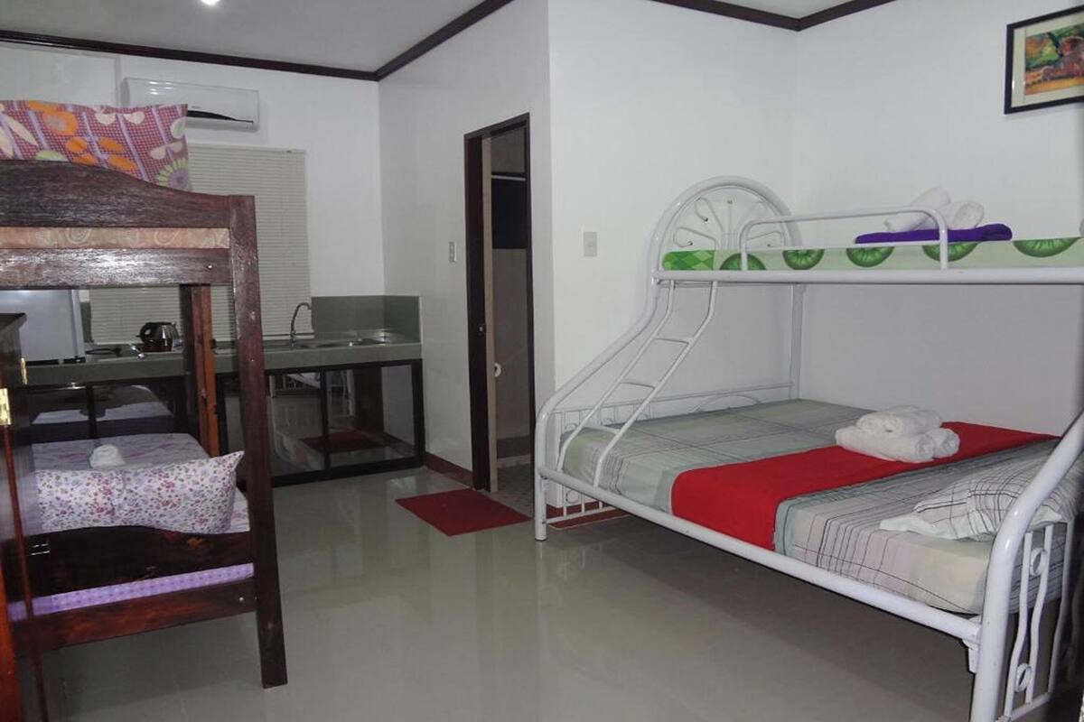 A bunk bed room with a desk and chair, a red mat, and a framed picture on the wall.