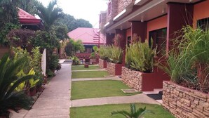A pathway leading to a building with a red roof, surrounded by well-maintained greenery and stone walls. - Citadel Bed and Breakfast (Puerto Princesa)