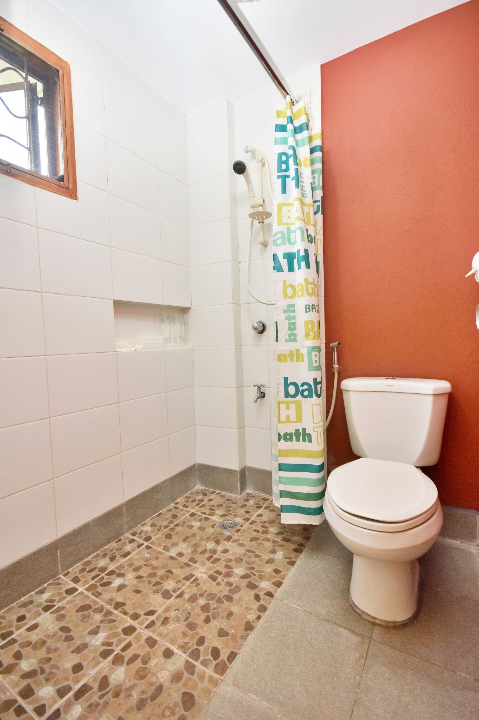 A bathroom with a shower, toilet, and tiled floor.