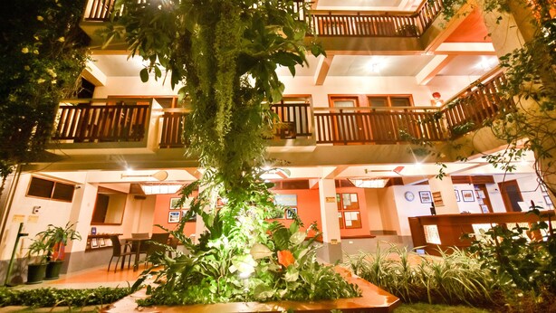 Un hôtel à plusieurs étages doté de balcons, de plantes d’intérieur et d’un hall d’entrée bien éclairé.