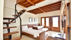 Une chambre avec un escalier en bois, un lit, une table de chevet et une porte donnant sur un balcon.