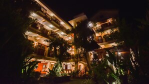 Un hôtel à plusieurs étages doté de balcons, entouré d’une végétation luxuriante.