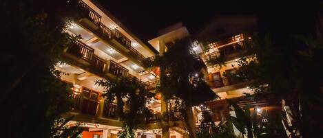 A multi-story hotel with balconies, surrounded by lush greenery.