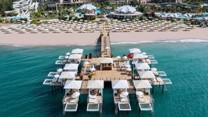 Vue aérienne d’un complexe hôtelier doté d’une plage, d’un toboggan aquatique et d’une jetée agrémentée de parasols et de chaises longues.