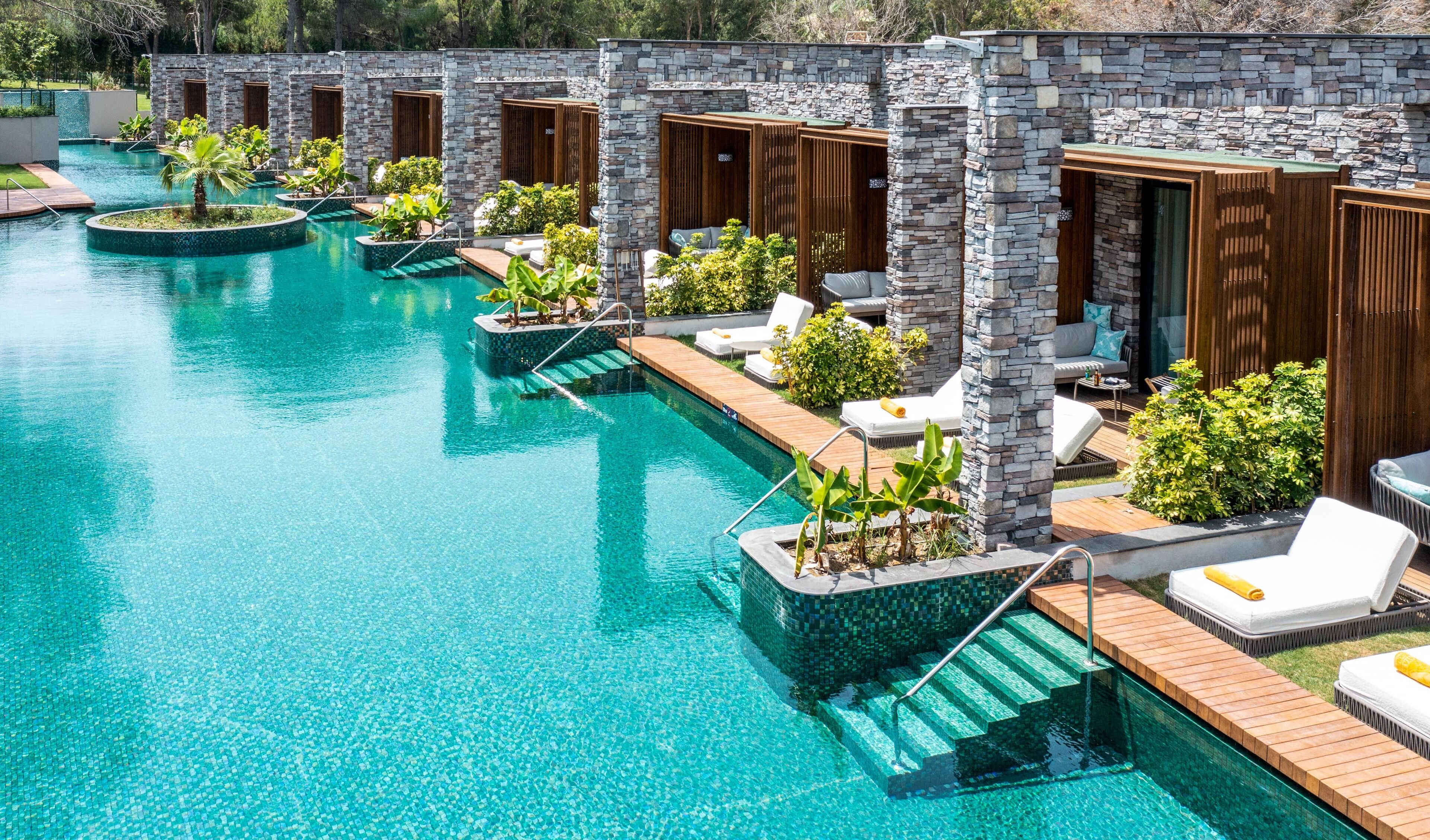 Un espace piscine doté de plusieurs chaises longues et de petites plantes.