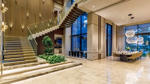 Un hall d’entrée spacieux avec un grand escalier, un coin repas et une grande fenêtre donnant sur l’extérieur.