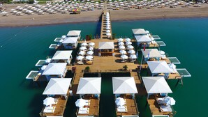 An aerial view of a floating hotel with multiple overwater bungalows, each with a deck and outdoor seating area. - Kaya Palazzo Golf Resort (Serik)