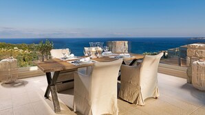 Une table à manger dressée pour deux personnes, avec vue sur la mer.