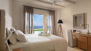 Une chambre à coucher avec un lit, un bureau, une lampe, un miroir et une vue sur la mer.