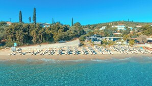 Une plage avec une eau d’un bleu limpide, des rangées de transats et des bâtiments en arrière-plan.