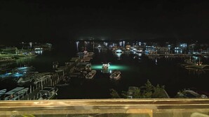 Un port de plaisance de nuit, avec des bateaux amarrés aux quais, éclairés par un éclairage d’ambiance.