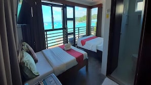 Une chambre d’hôtel avec deux lits, une télévision et vue sur la mer.