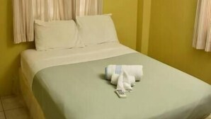 A single bed with a mosquito net, white pillows, and a green bedspread. - Aanola Villas (Castries)