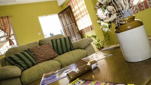 A living room with a green sofa, a wooden coffee table, and a vase with dried flowers. - Aanola Villas (Castries)