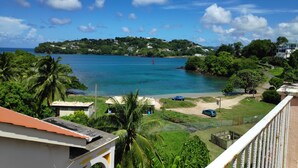 A coastal view with a clear sky, a beach, and a hill with buildings. - Aanola Villas (Castries)