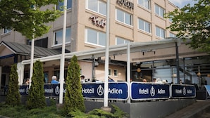 A hotel with a sign reading "Hotel Adlon" and a flagpole with a blue flag.