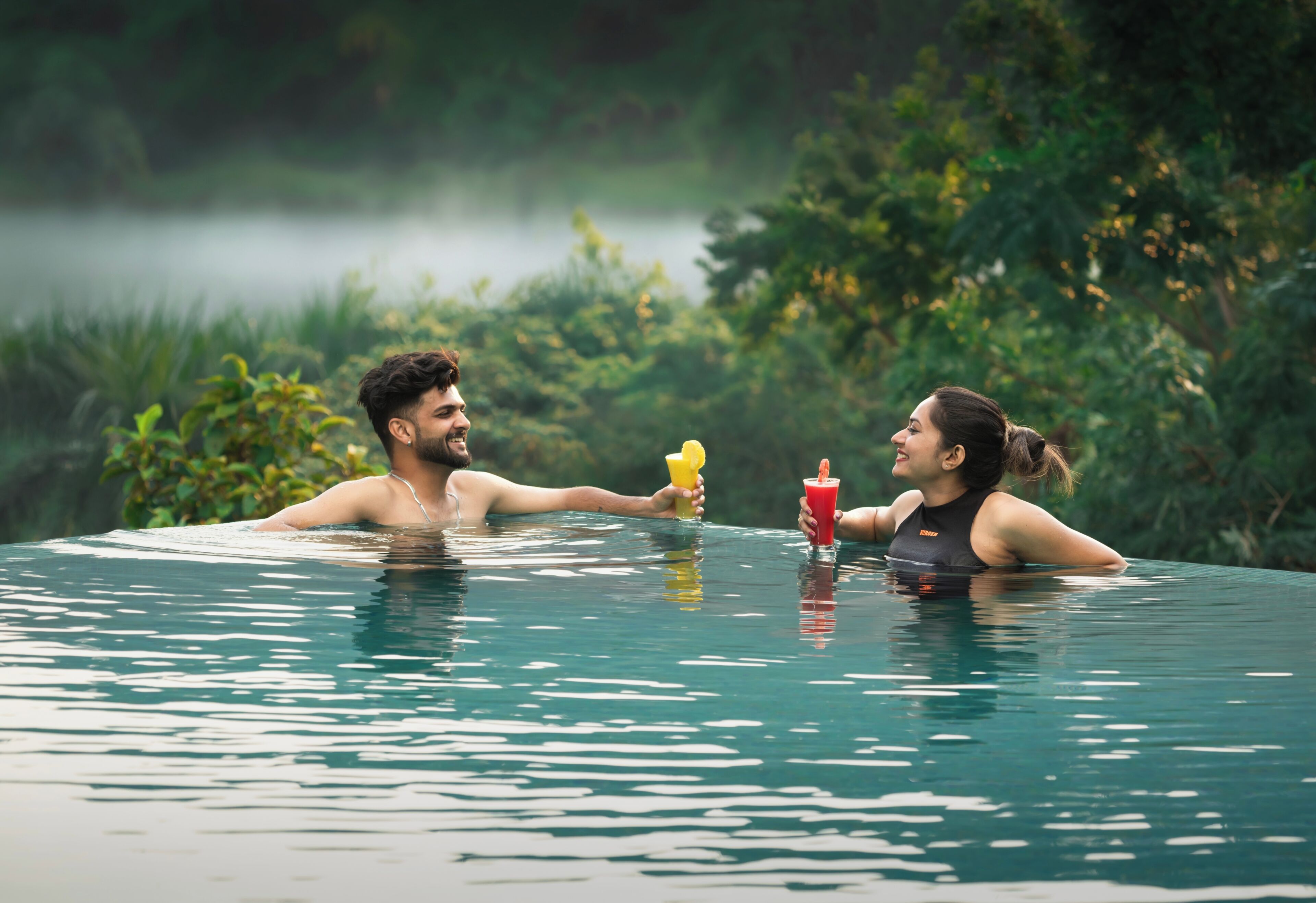 A couple in a clear pool with a natural backdrop.