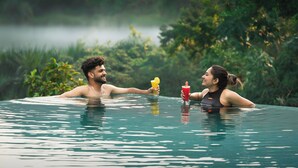 A couple in a clear pool with a natural backdrop.