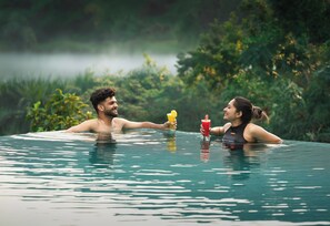 A couple in a clear pool with a natural backdrop.