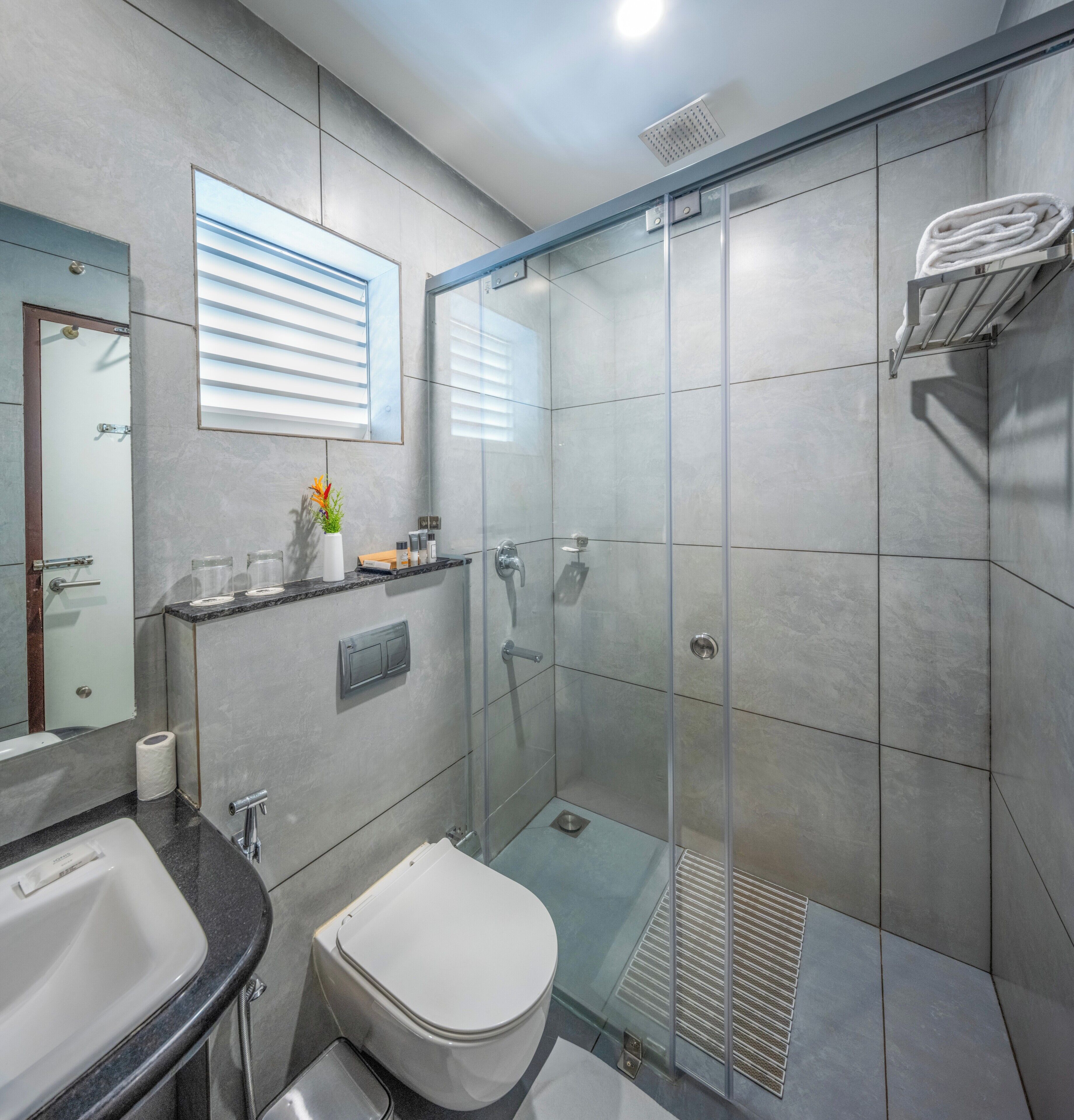 Un baño moderno con cabina de ducha de vidrio, inodoro, lavabo y espejo.