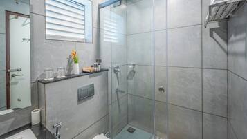 Un baño moderno con cabina de ducha de vidrio, inodoro, lavabo y espejo.