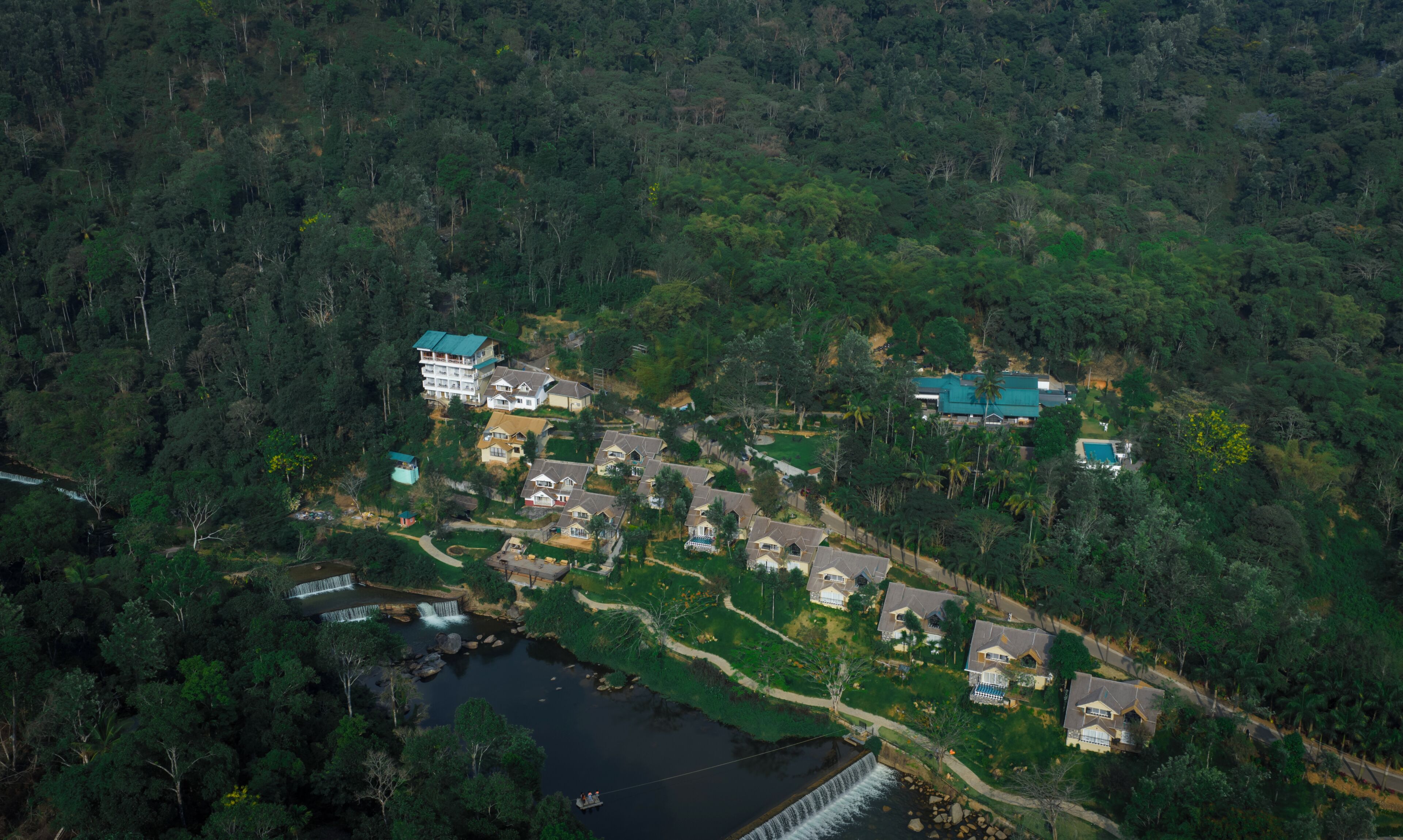 Vue aérienne d’un quartier résidentiel avec des maisons, une petite cascade et un pont.