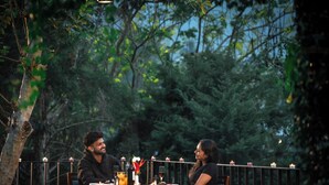 Un couple dînant en plein air, à la lueur de bougies, autour d’une table dressée pour deux.