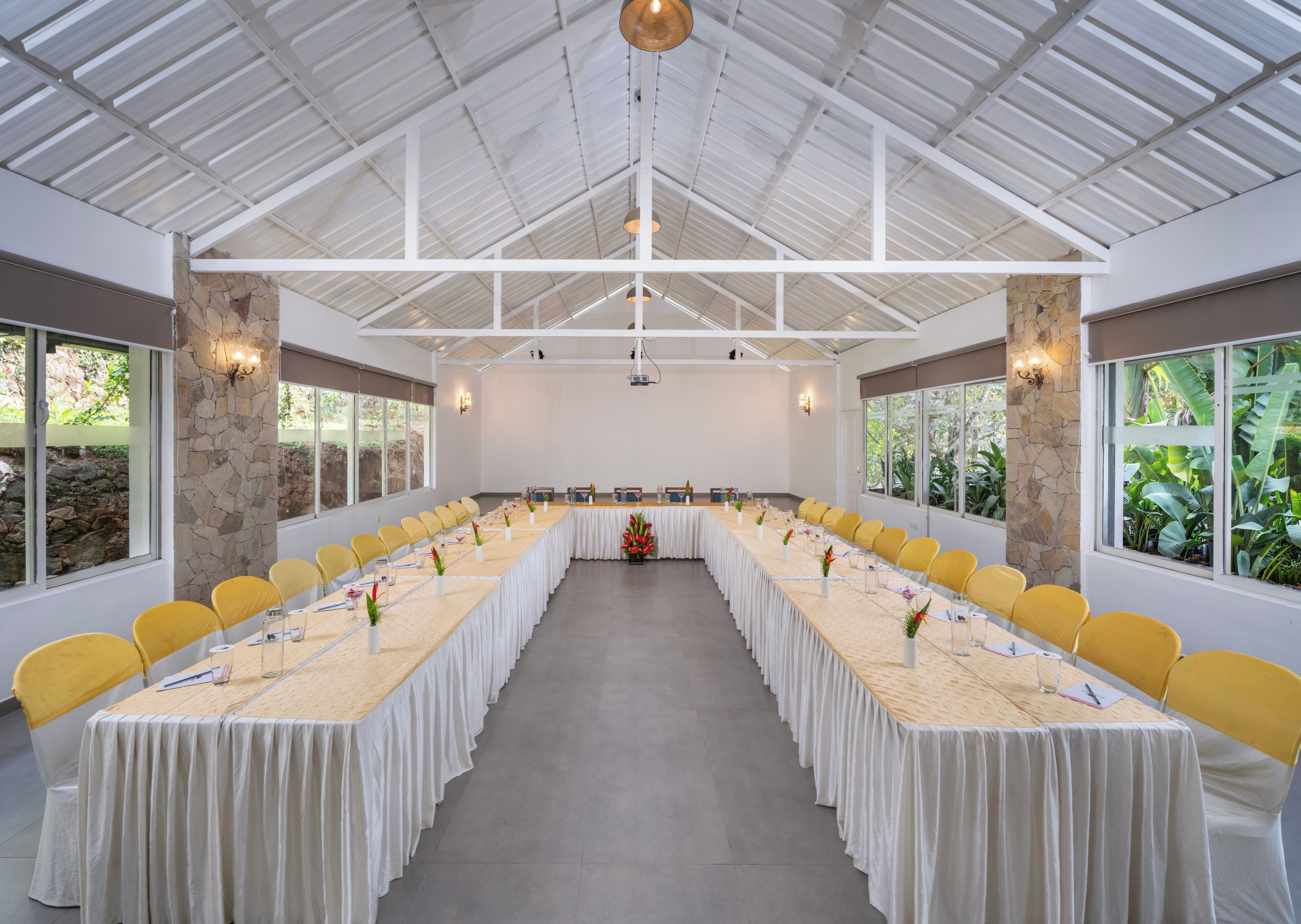 A conference room with a long table, yellow chairs, stone pillars, and large windows.