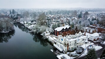 A snow-covered riverside town with a prominent hotel featuring multiple buildings and a dock.