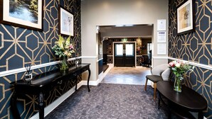A hotel lobby with a geometric patterned wall, a reception desk, a seating area, and framed artwork on the walls. - Thames Riviera Hotel, Sure Hotel Collection by Best Western (Maidenhead)