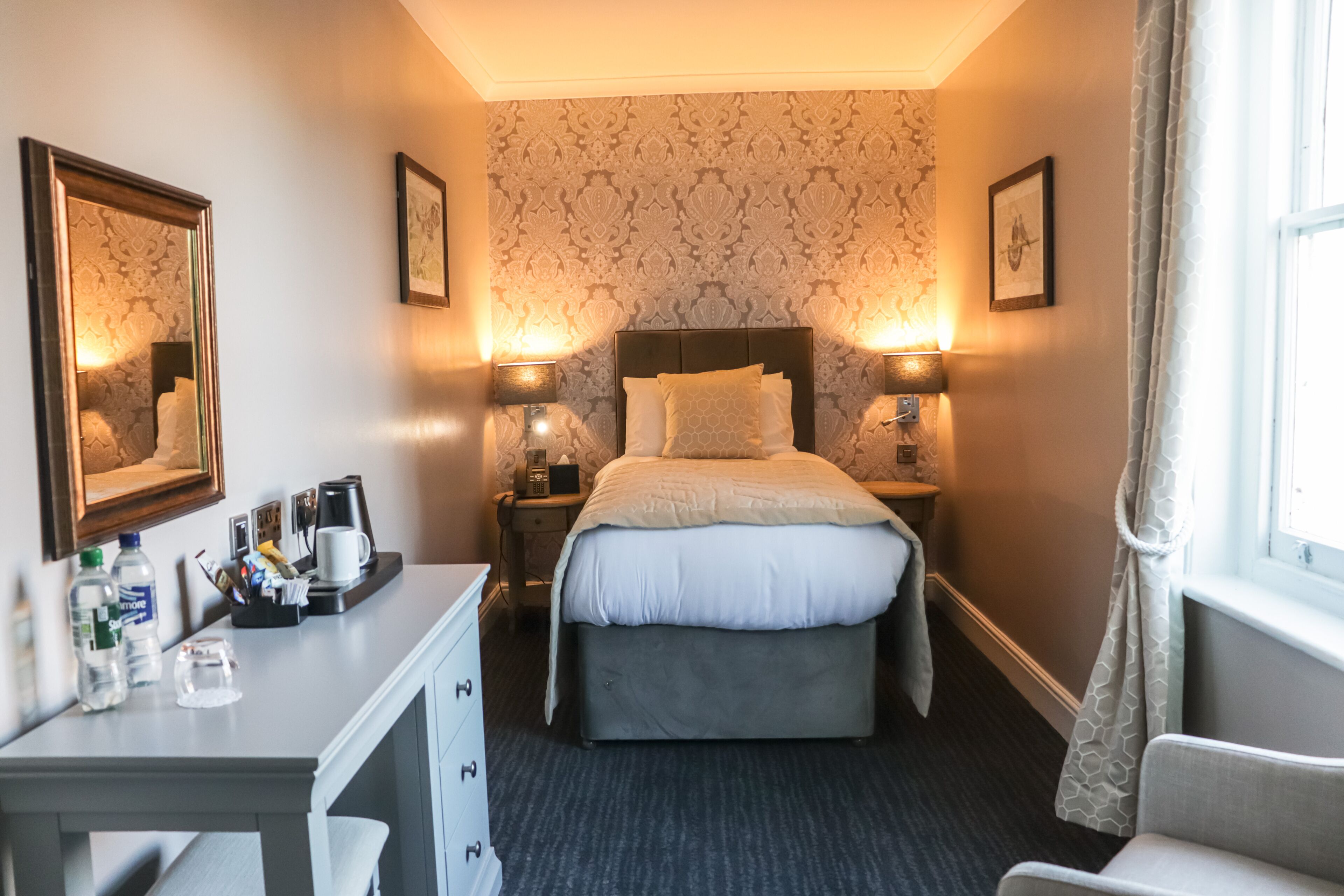Una habitación de hotel con cama, mesitas de noche, escritorio y una silla.