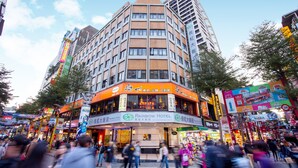 A multi-story hotel with a prominent Rainbow Hotel sign, surrounded by busy streets and various shops. - Rainbow Hotel (Taipei)