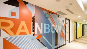 A hallway with a colorful wall mural featuring geometric shapes and the word "RAINBOW". - Rainbow Hotel (Taipei)