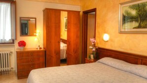 A hotel room with a bed, a dresser, a mirror, a radiator, and a painting on the wall. - Hotel Belvedere (Roccaraso)