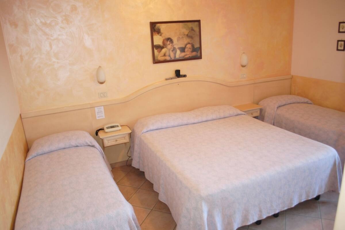 Una habitación de hotel con dos camas individuales, una mesita de noche con teléfono y un cuadro en la pared.