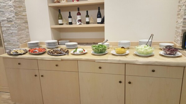 Buffet com diversos pratos e seleção de vinhos.