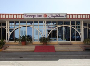 A building with a reception area, large windows, and potted plants.
