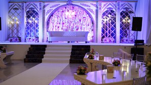 A formal event space with a stage, seating, and decorative elements. - Ramee Dream Resort (Seeb)