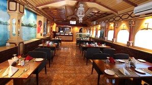 A restaurant with a high ceiling, wooden beams, and a mural of a landscape. Tables are set with plates, glasses, and cutlery. - Ramee Dream Resort (Seeb)