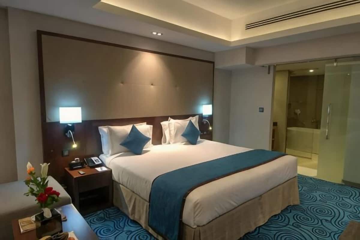 Une chambre dâhĂŽtel avec un grand lit, des lampes de chevet, un bureau avec un tĂ©lĂ©phone et un espace douche.