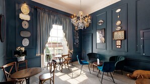 A room with a chandelier, blue and brown chairs, a table, and a dog. - Edgar Townhouse (Bath)