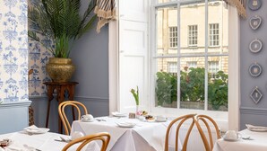 A dining area with white tablecloths, wooden chairs, and a large potted plant. - Edgar Townhouse (Bath)