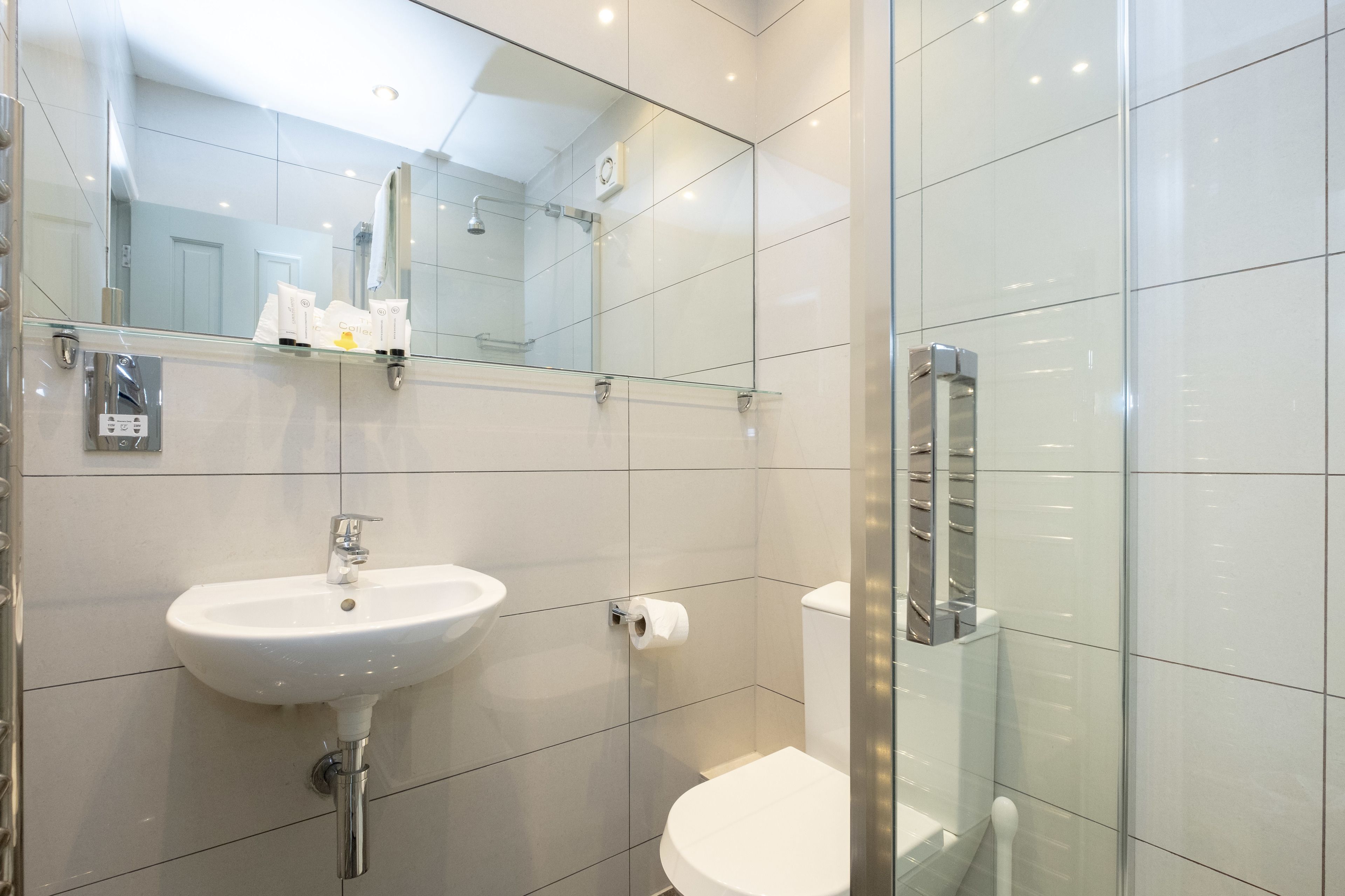 A modern bathroom with a glass shower enclosure, a white sink, and a toilet.