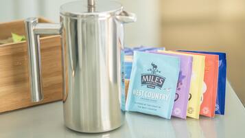 Une cafetière en acier inoxydable et des sachets de thé du mélange «
West Country
» sont posés sur une surface en bois.