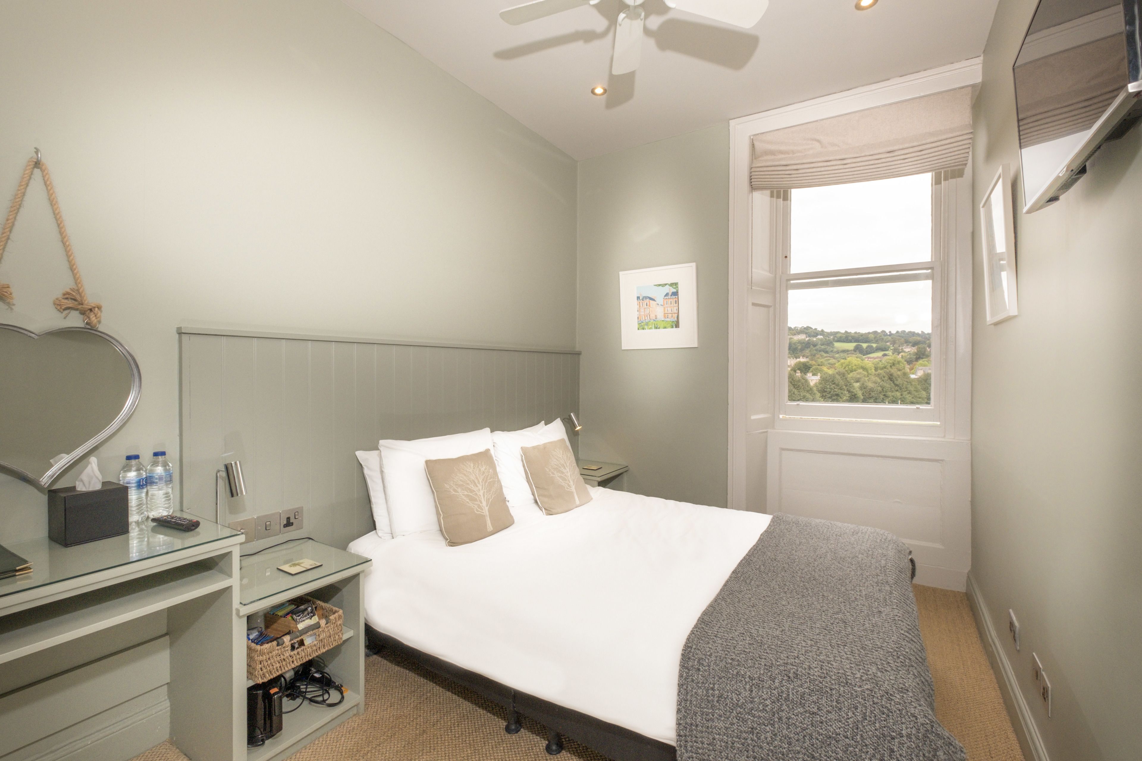 A hotel room with a bed, bedside table, and a window with a view.