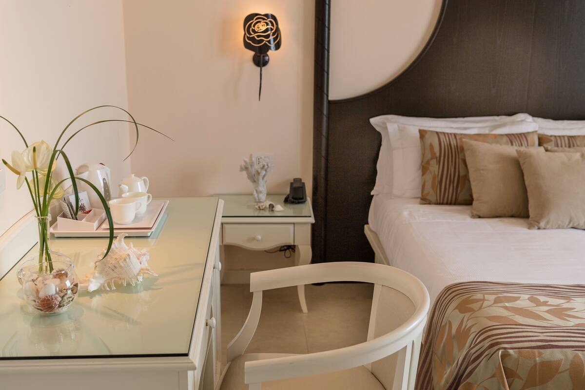 A hotel room with a bed, a nightstand, a desk, and a chair.