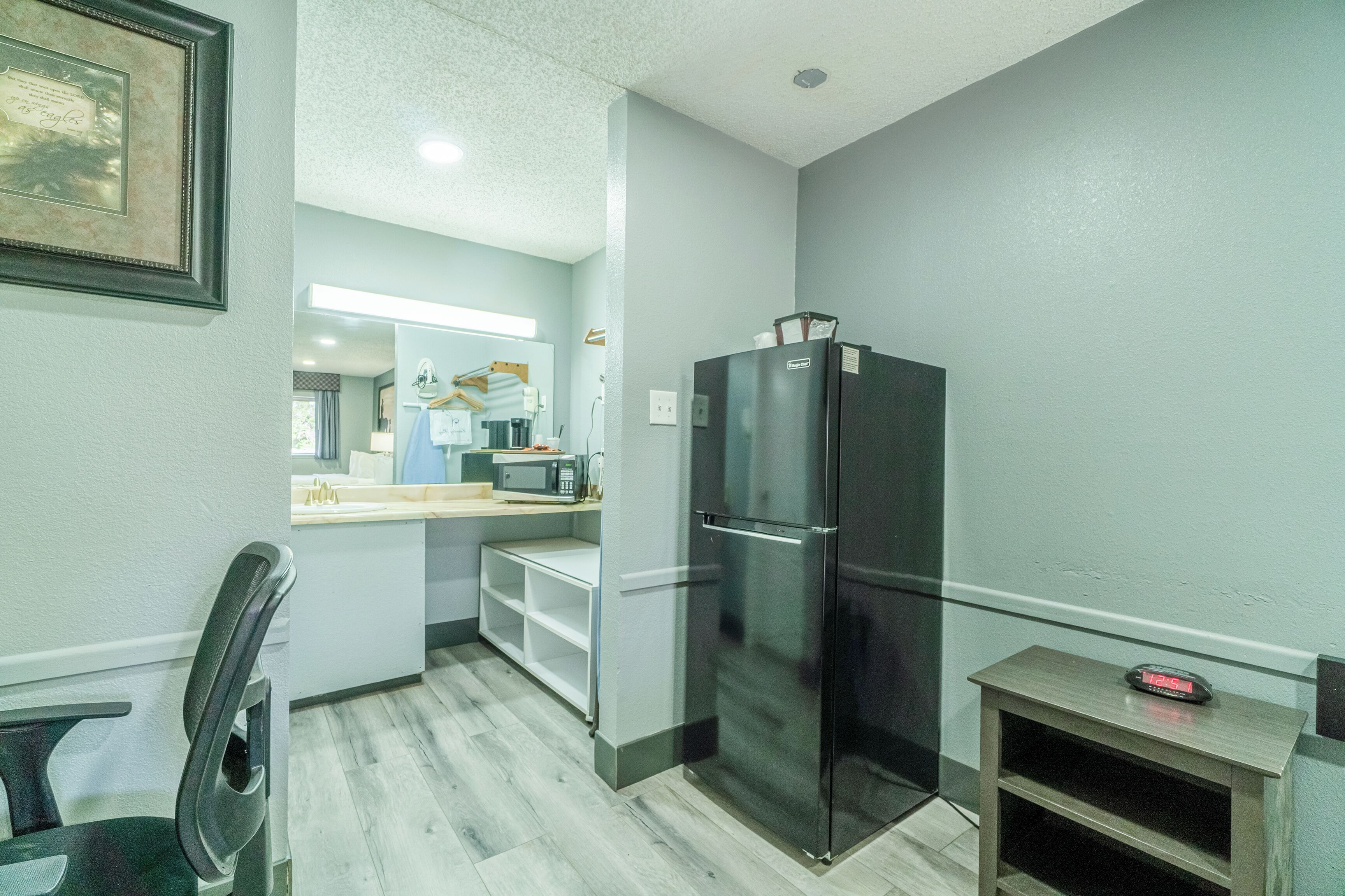 A compact kitchen with a refrigerator, microwave, and a small dining area with a chair and table.