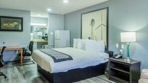 A hotel room with a bed, desk, chair, and a lamp. - Purple Sage By OYO Snyder TX (Snyder)