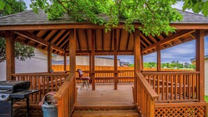A wooden deck with a pergola, a barbecue grill, and a trash can. - Purple Sage By OYO Snyder TX (Snyder)